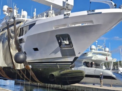 Superyacht suspended in haul-out slings during underwater hull survey preparation