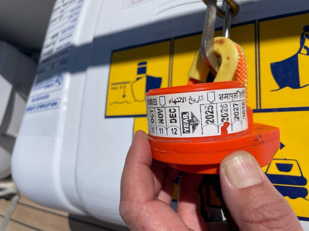 Marine surveyor checking hydrostatic release unit expiration date during routine boat safety inspection
